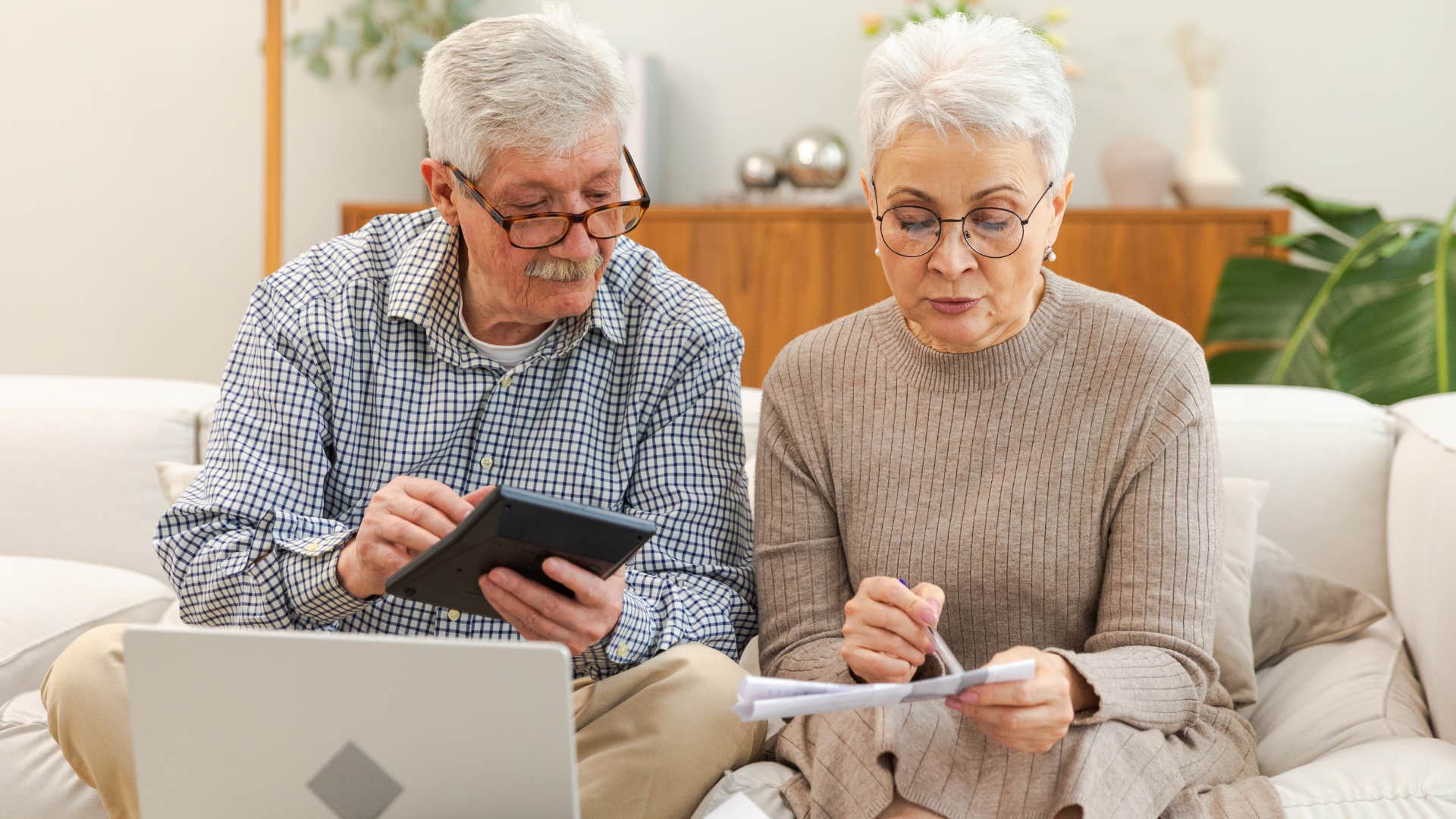 Older couple doing bills on their couch