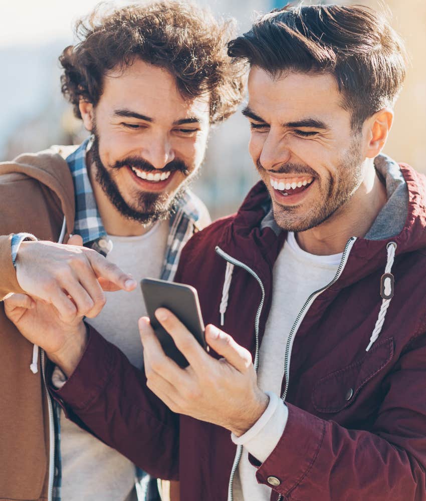 two male friends looking at phone and laughing