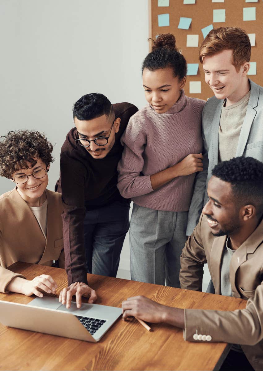 group of coworkers looking at an open laptop