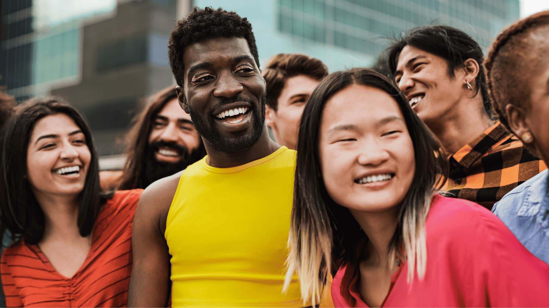 Group of people in colorful clothing stand outside and laugh