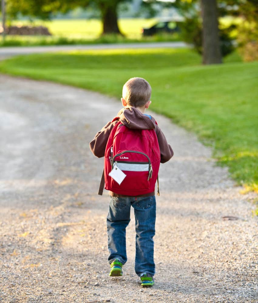 little boy walking on path with backpack