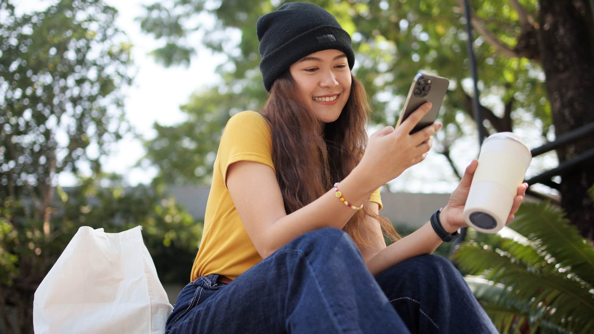 Gen Z woman smiling and looking at her phone.