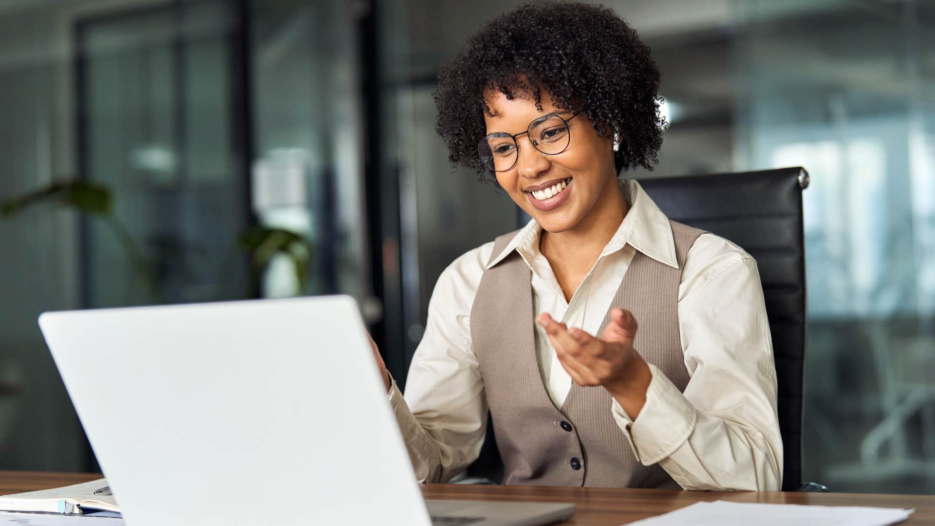 Gen Z woman smiling and talking on her laptop.