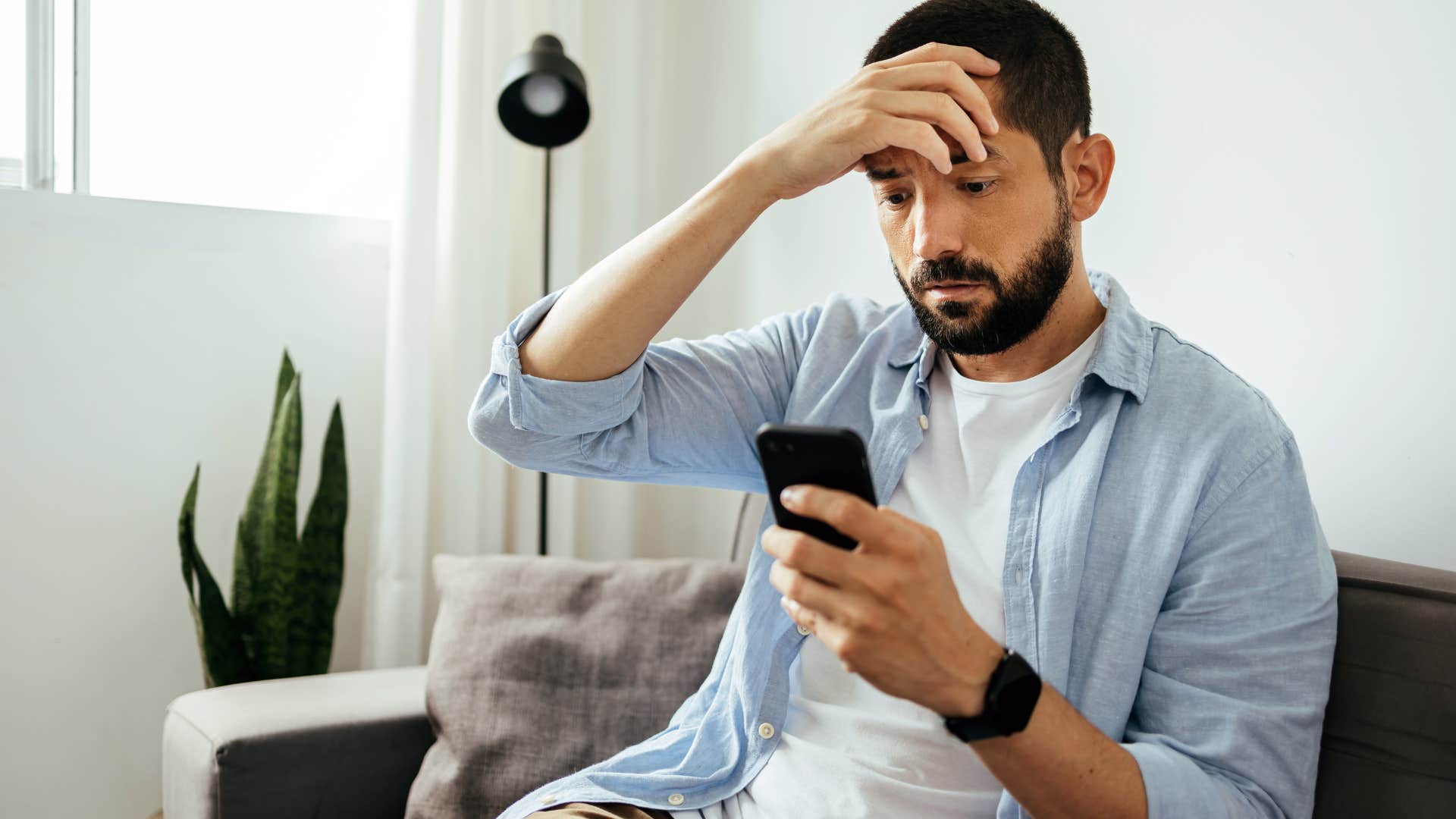 Gen Z man looking upset staring at his phone.