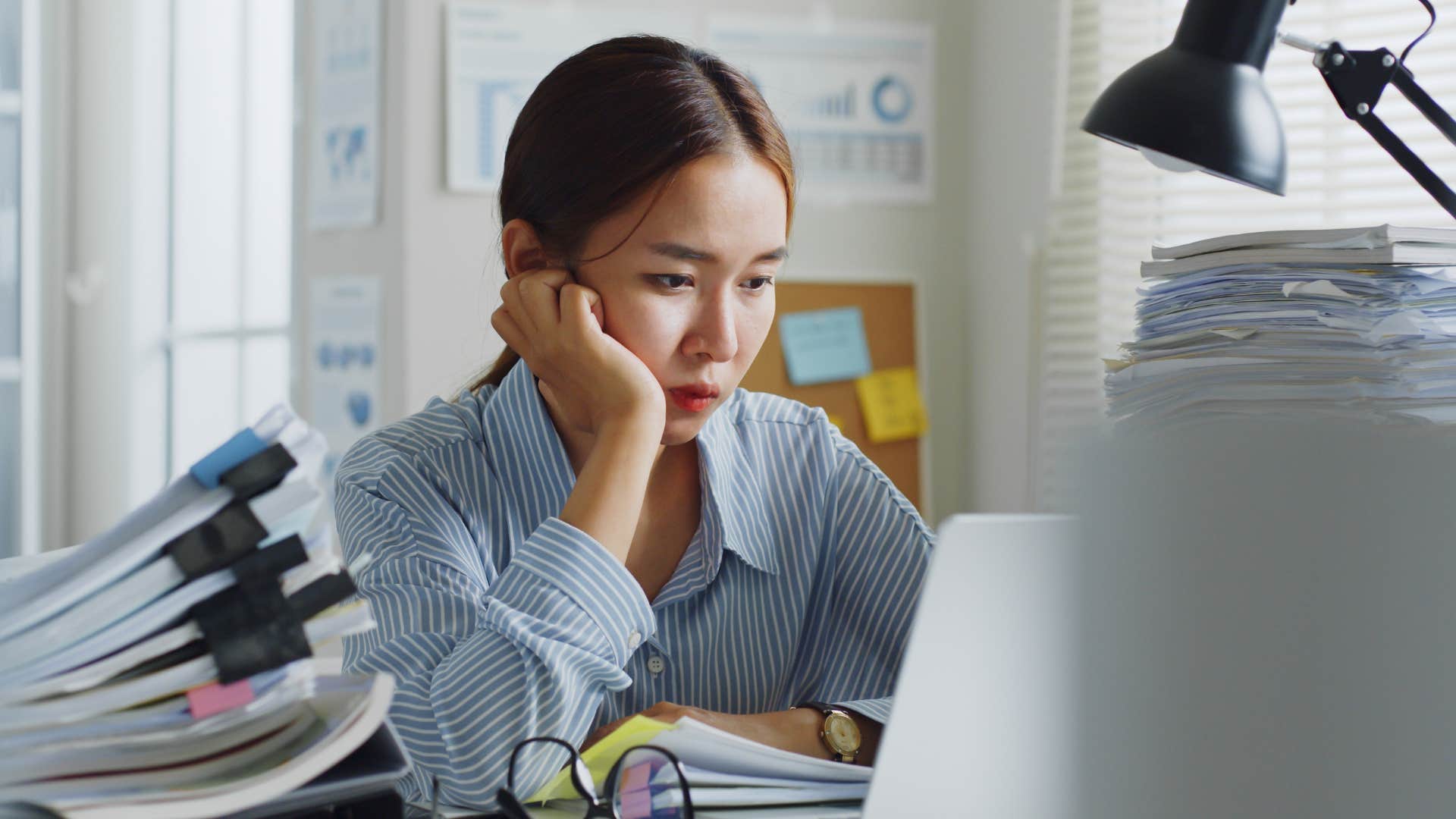 Young woman looking tired staring at her laptop.