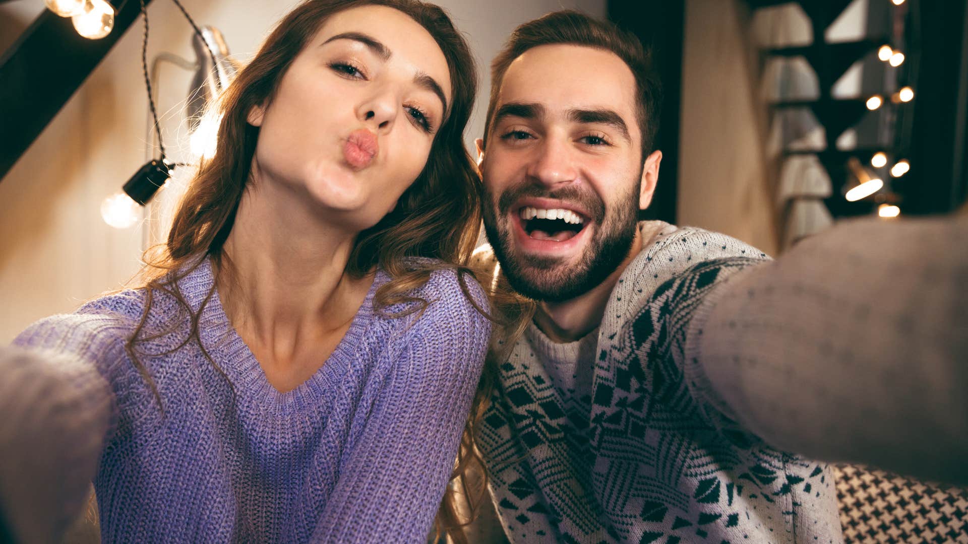 Cheerful young friends sitting together on a couch taking selfies