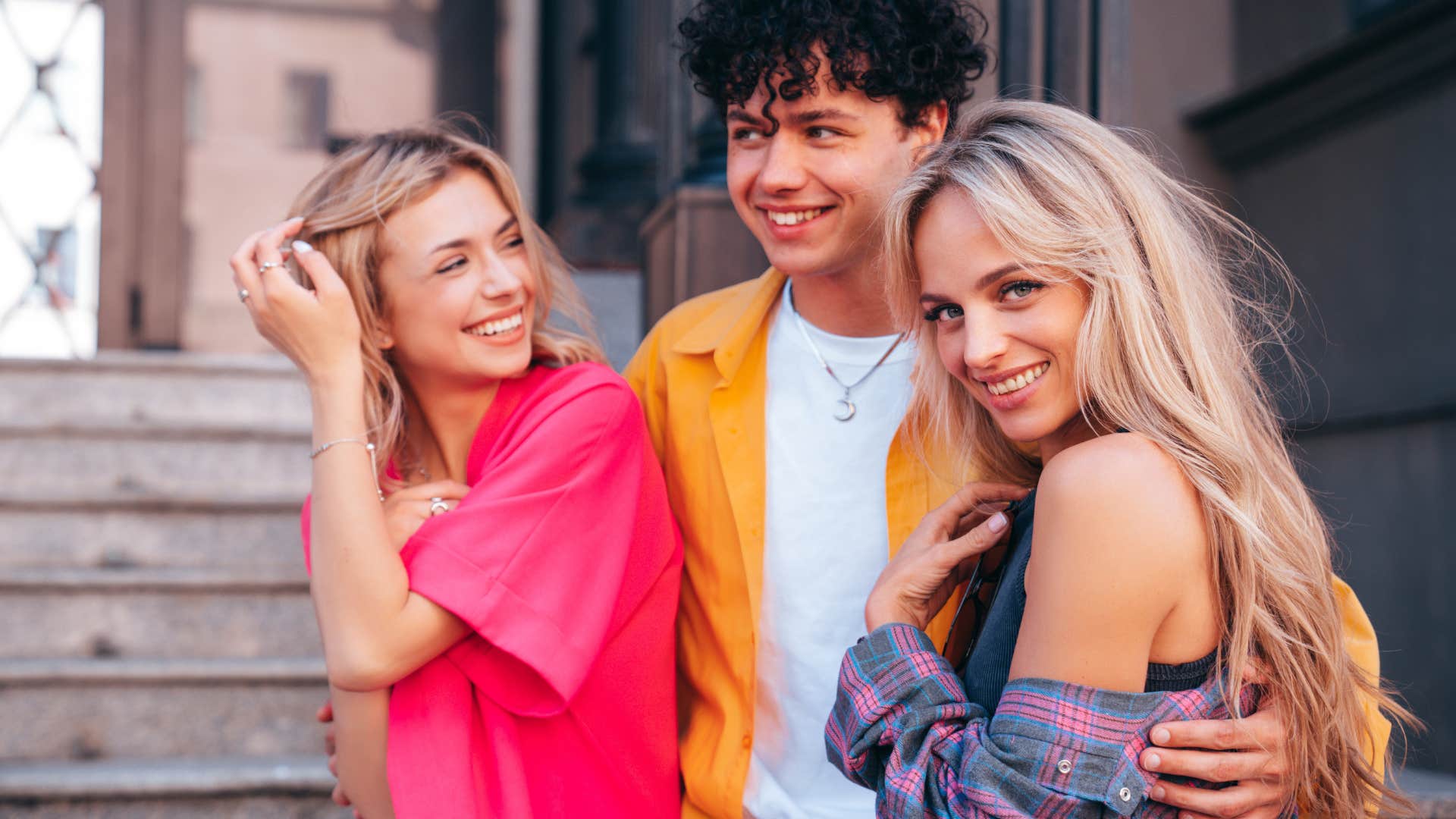 Group of young three stylish friends posing in the street.