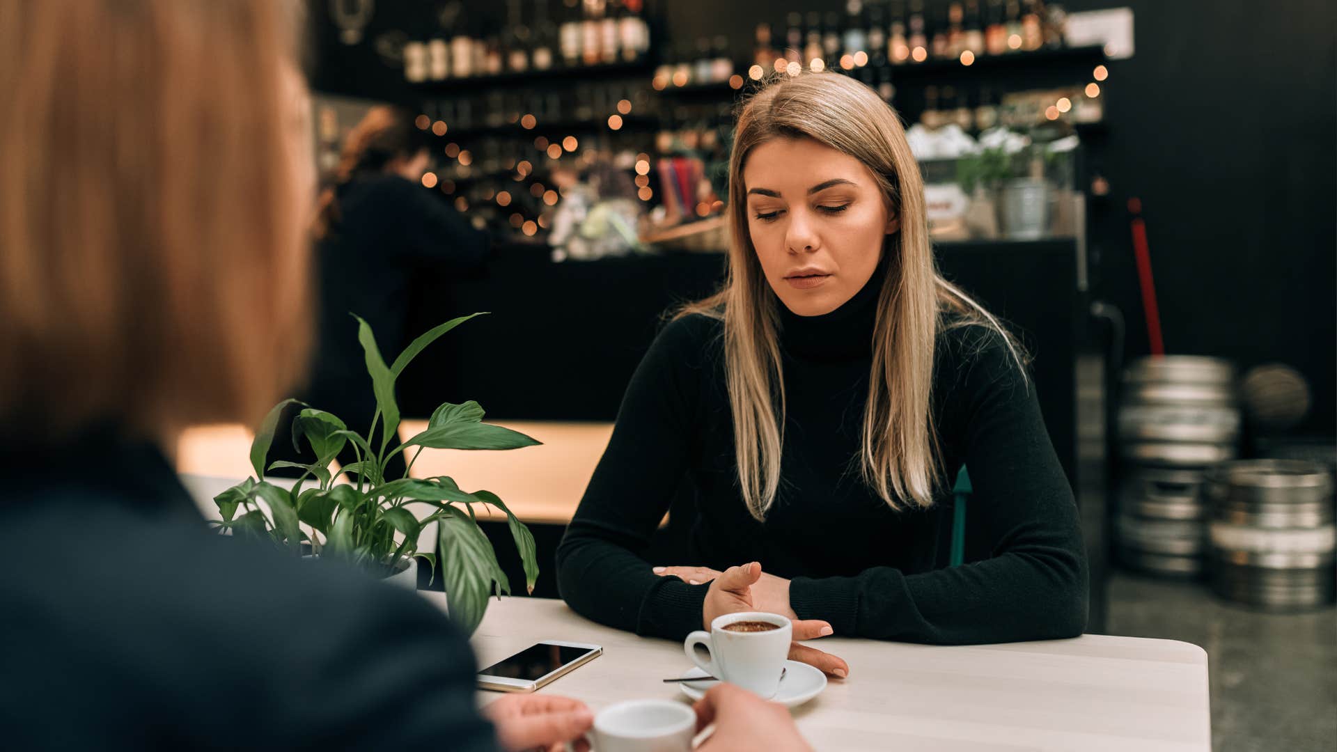 Two girl friends in a cafe having a serious conversation over a cup of coffee