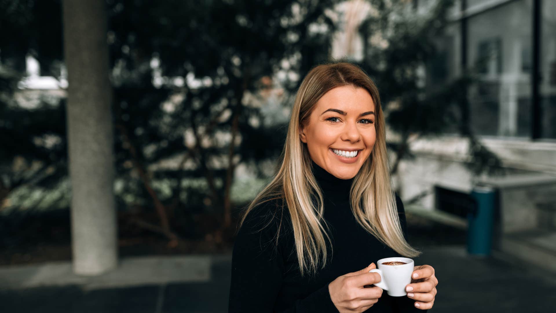 Portrait of a smiling blonde woman holding a cup of coffee