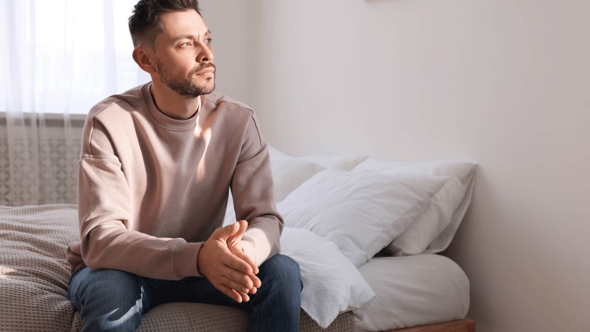 man sitting on bed, thinking