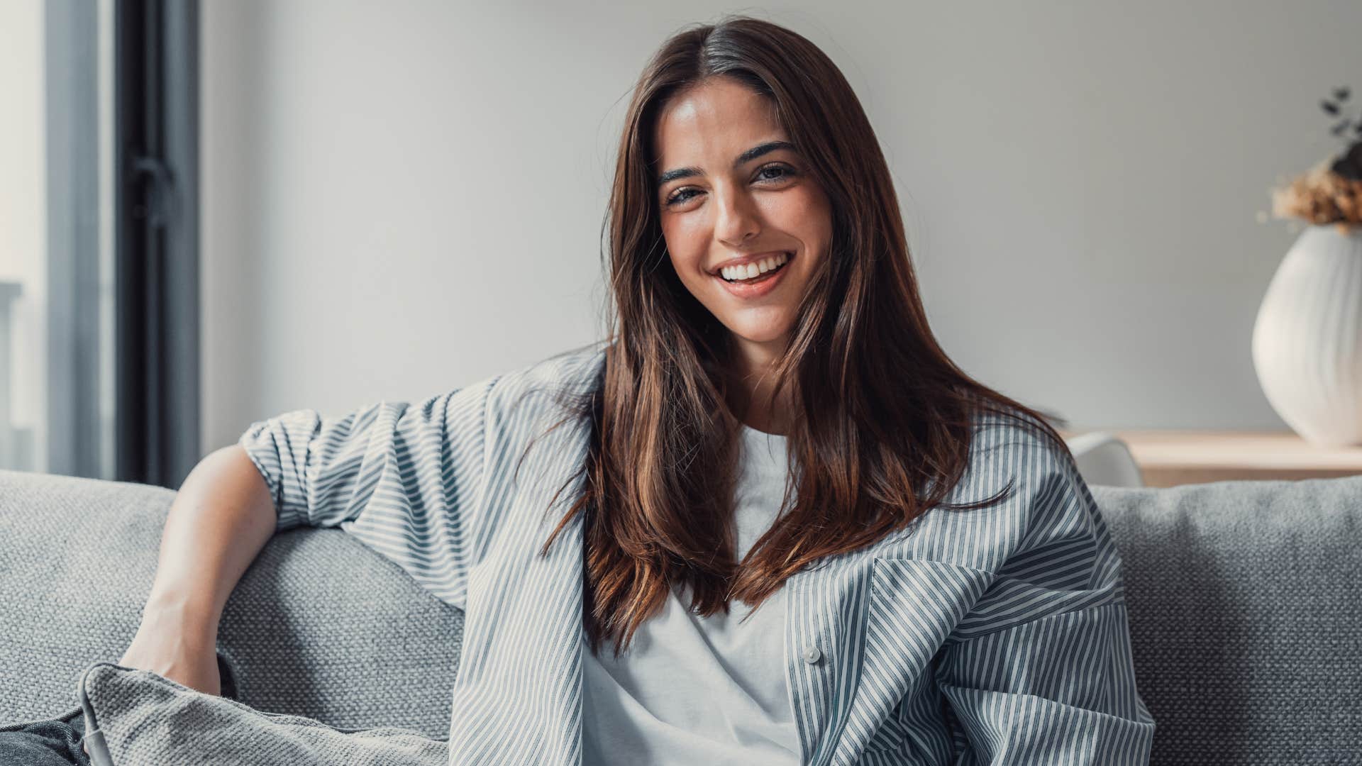 Woman smiling while sitting on her couch.