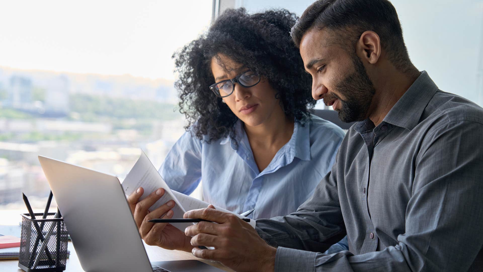 Serious woman looking at a piece of paper with her co-worker. 