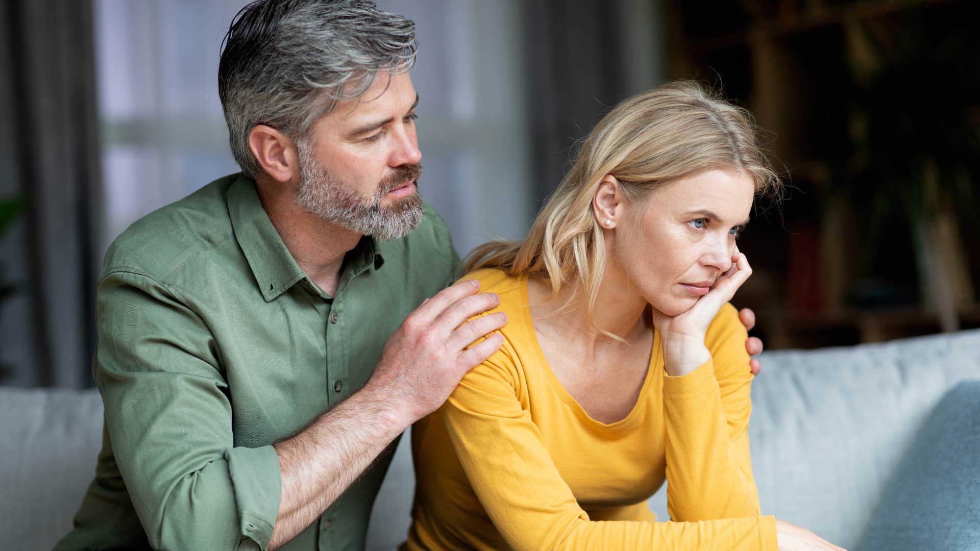 Man comforting his upset wife on the couch.