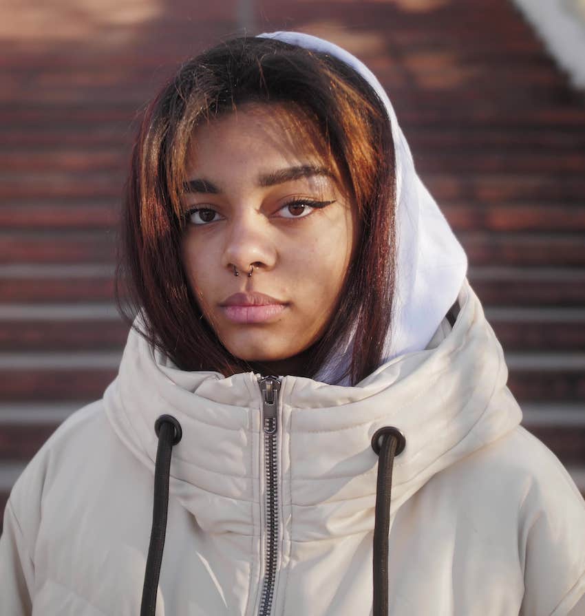 Woman with hood up look s at camera