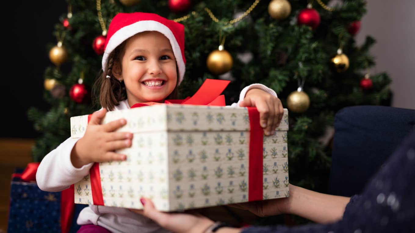 Happy little girl holding gift for Christmas