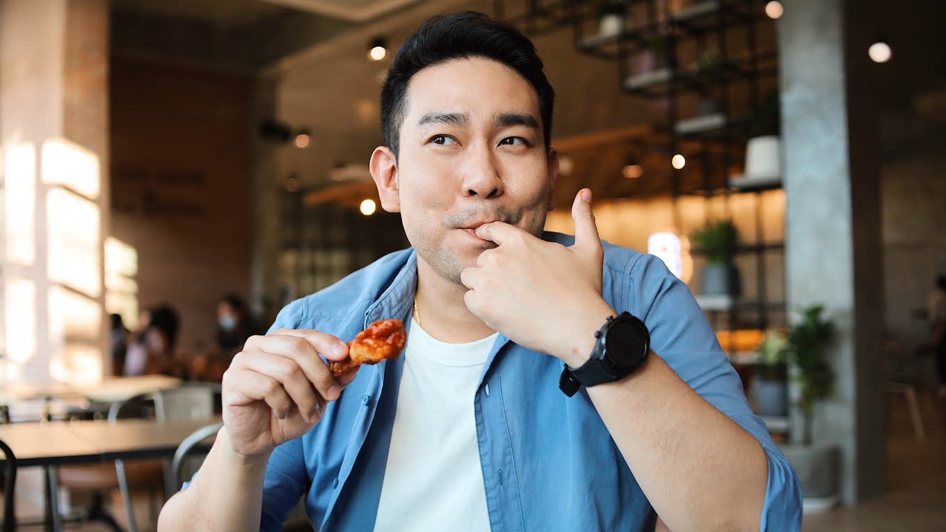 man eating chicken wings with his hands