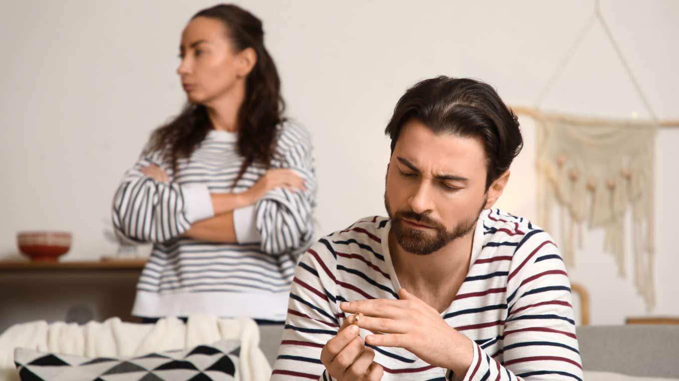 Unhappy man taking off his wedding ring at home