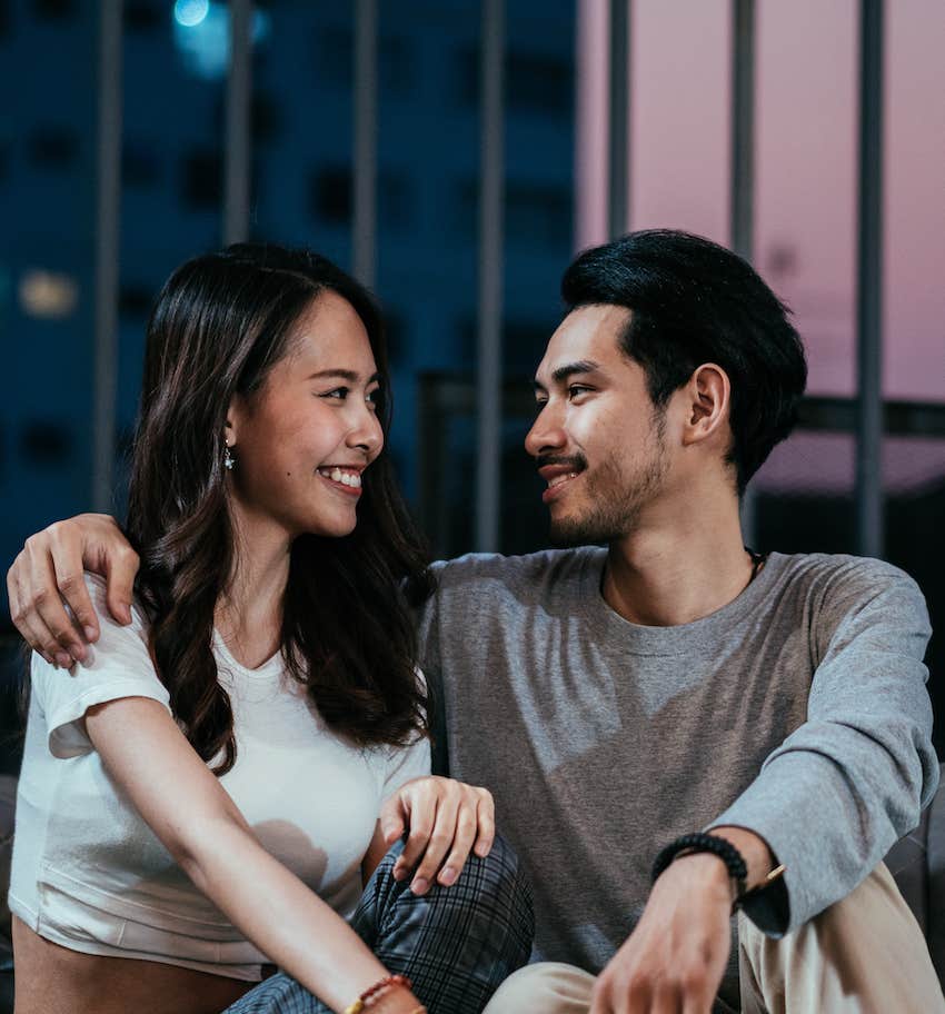 Man has arm around smiling woman as they talk slowly