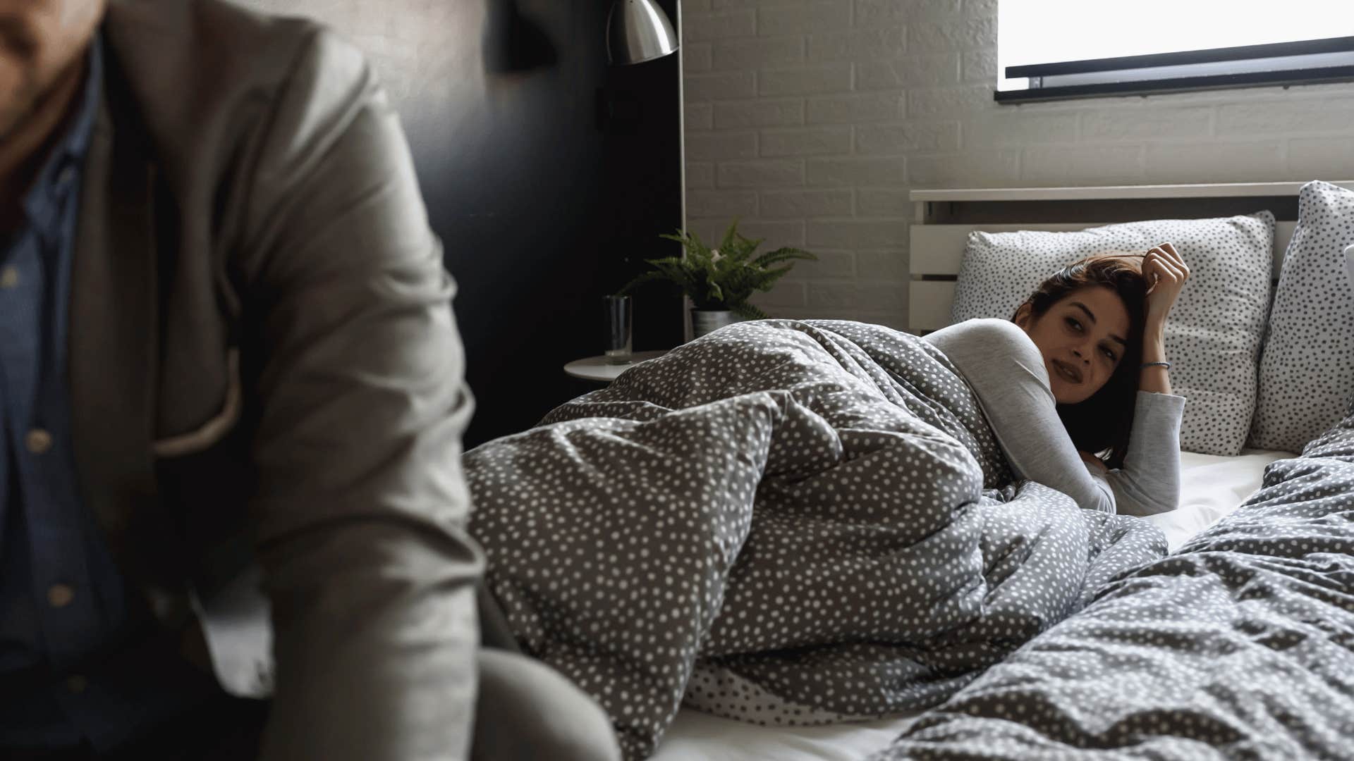 man leaving bed with woman in it