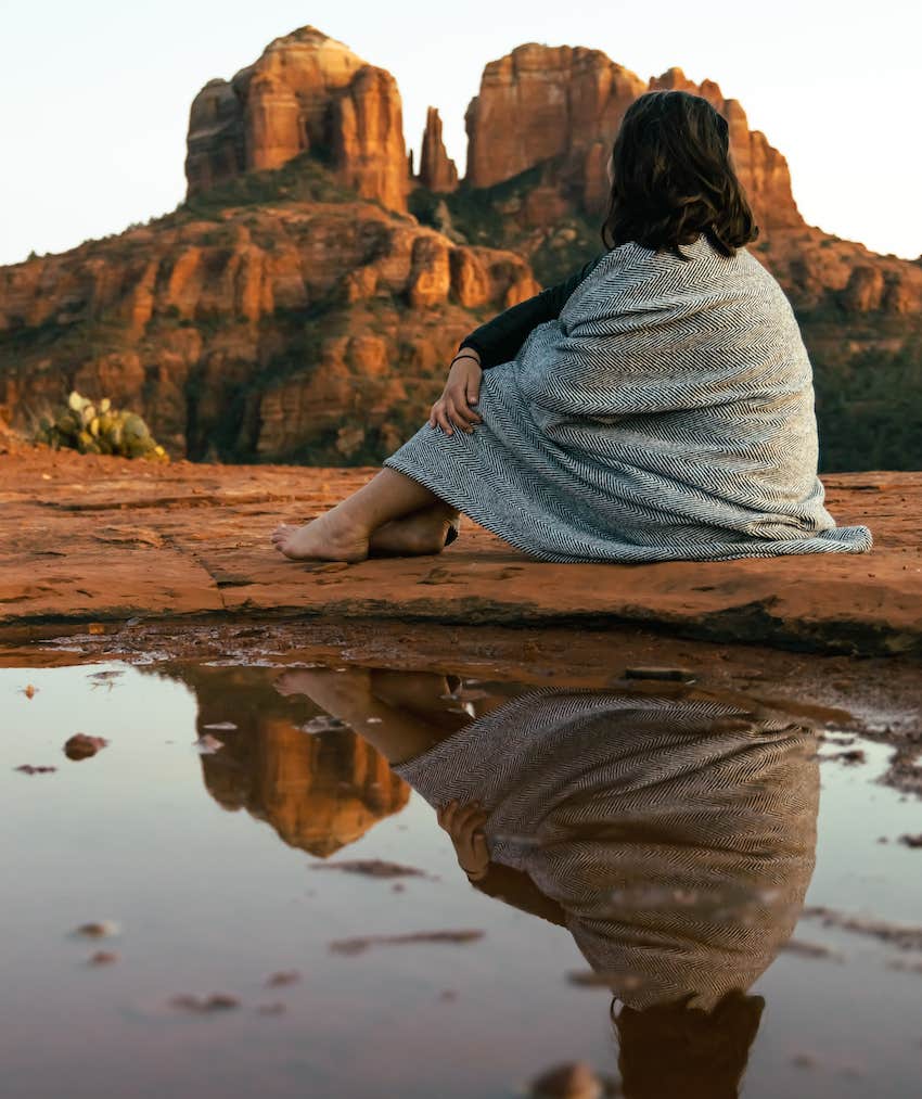 Person sits near water in desert cliff area