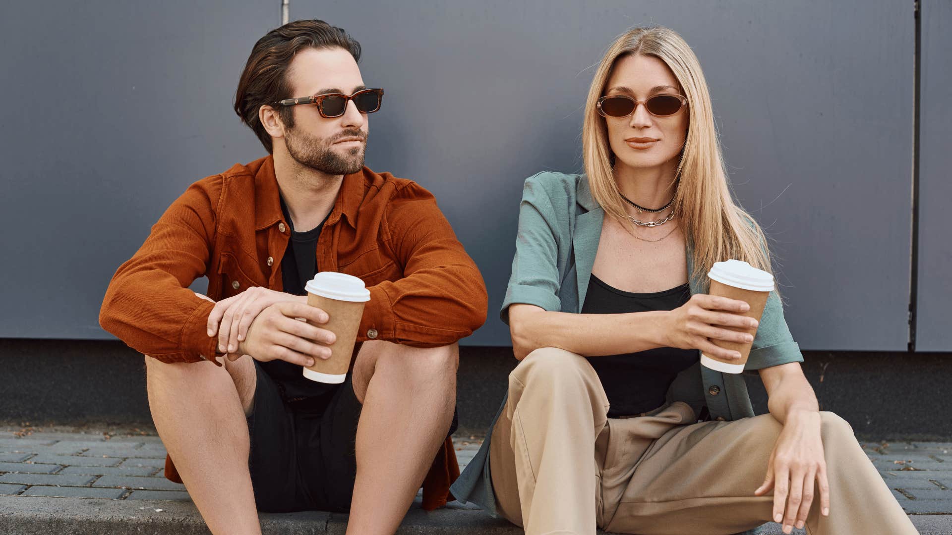 Man sits near but not touching woman, both wear sunglasses