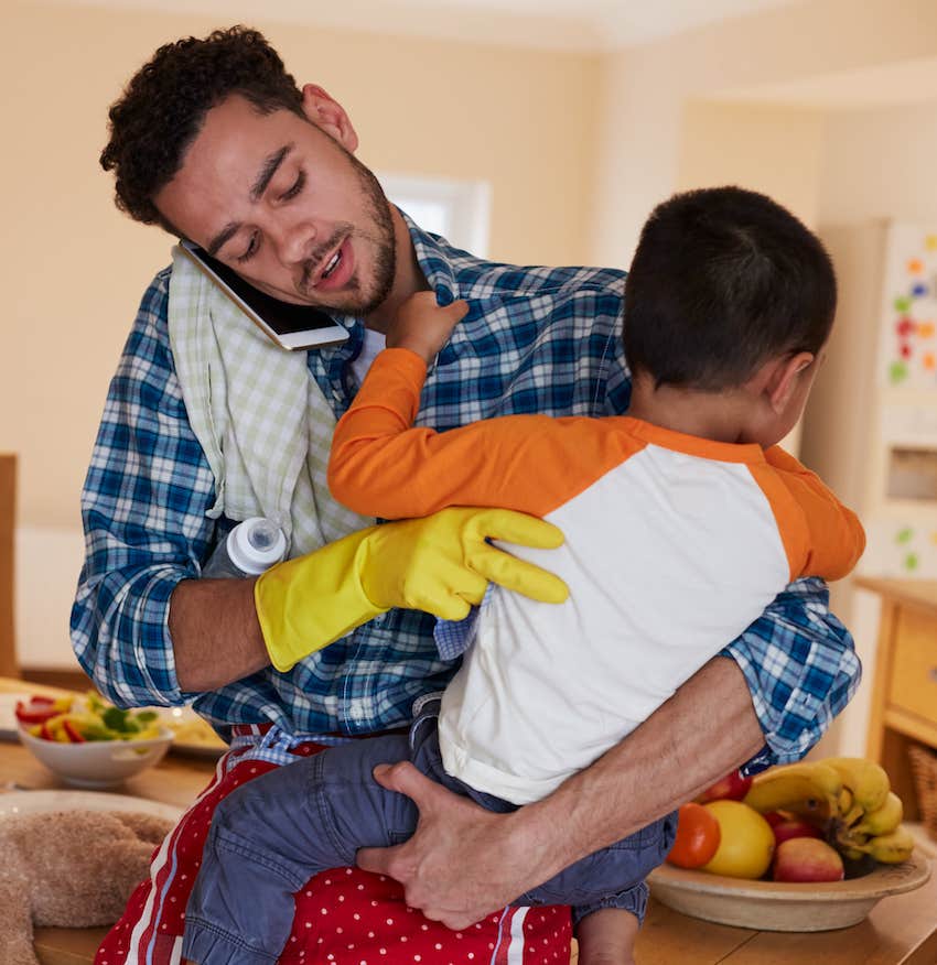 While cleaning kitchen, father holds young child 