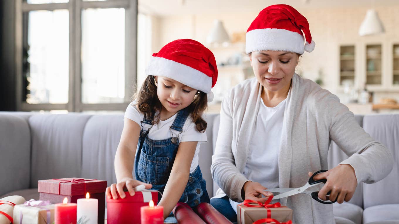 Young mother and little girl daughter using paper for wrapping Christmas presents