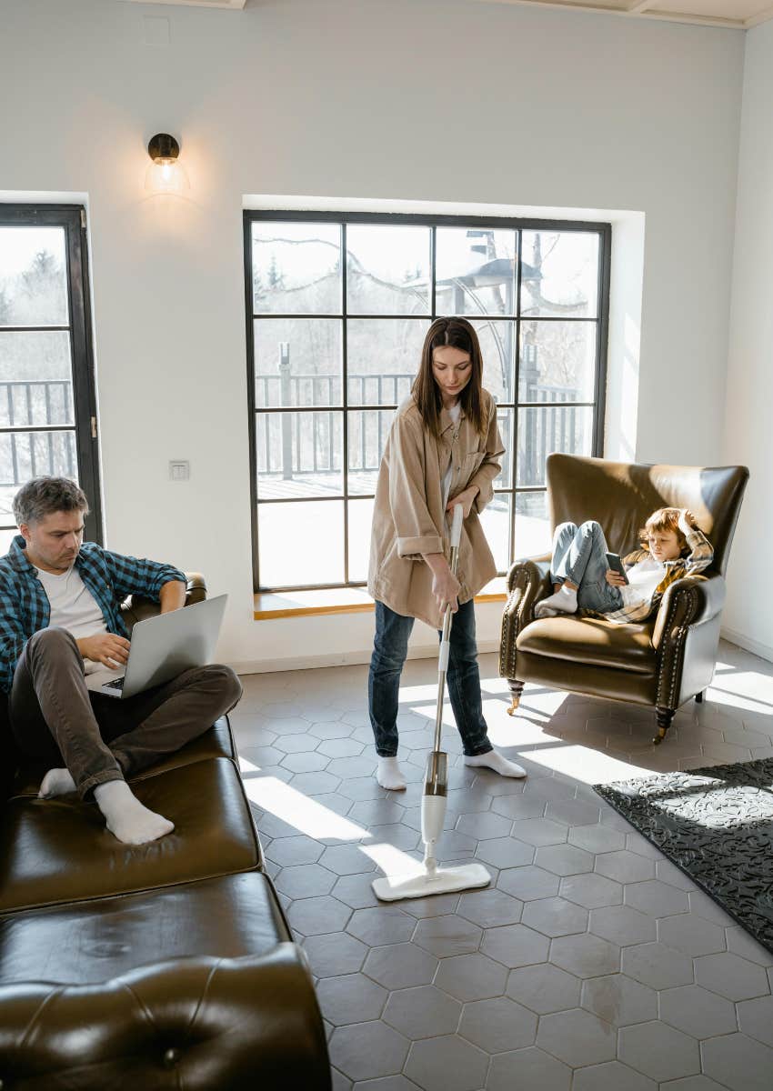 mom mopping the floor while husband and kid sit there