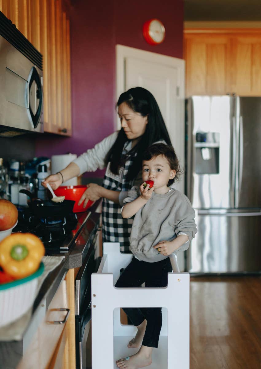 mom cooking in the kitchen while taking care of her kid