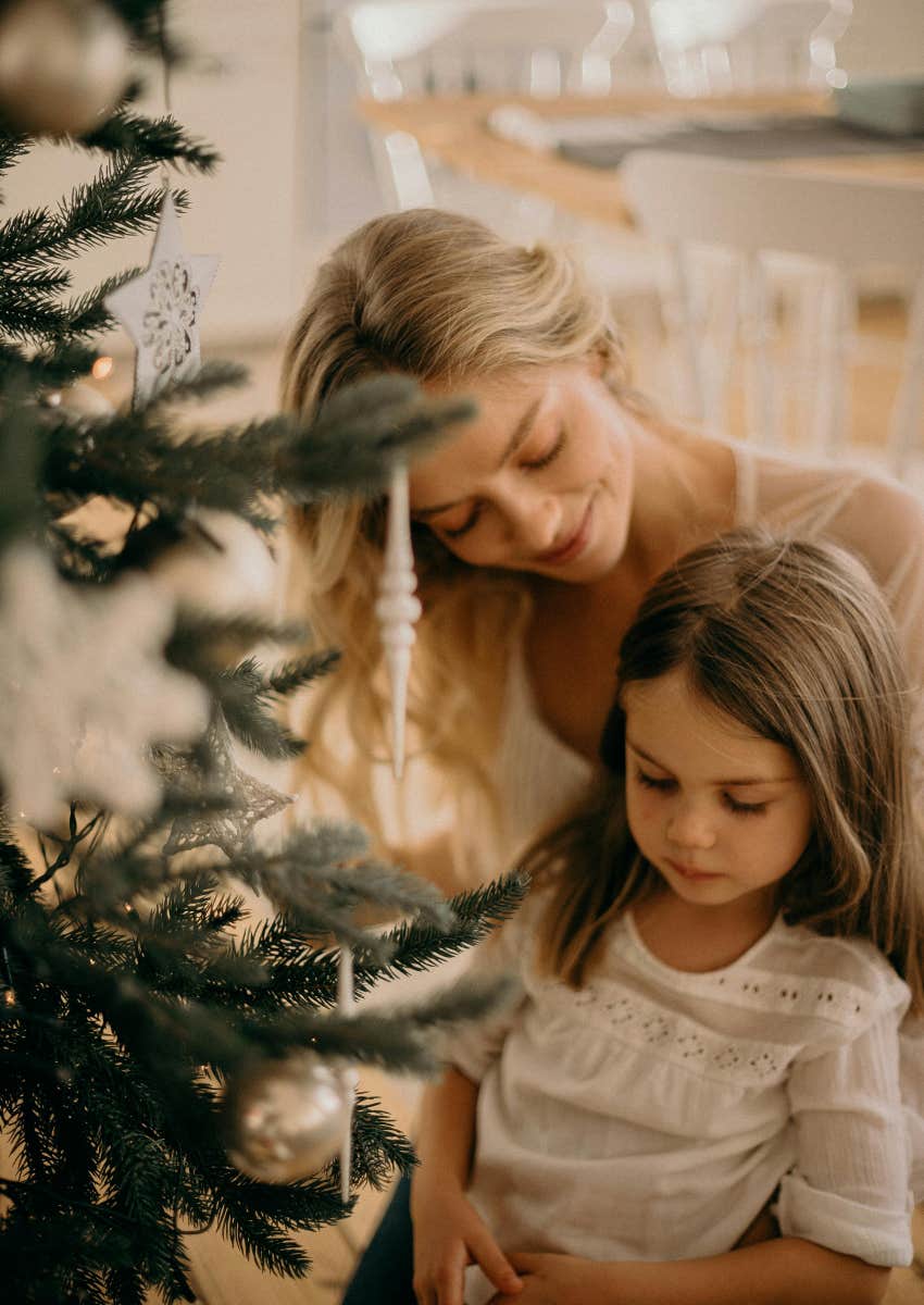 mom and daughter standing together by Christmas tree