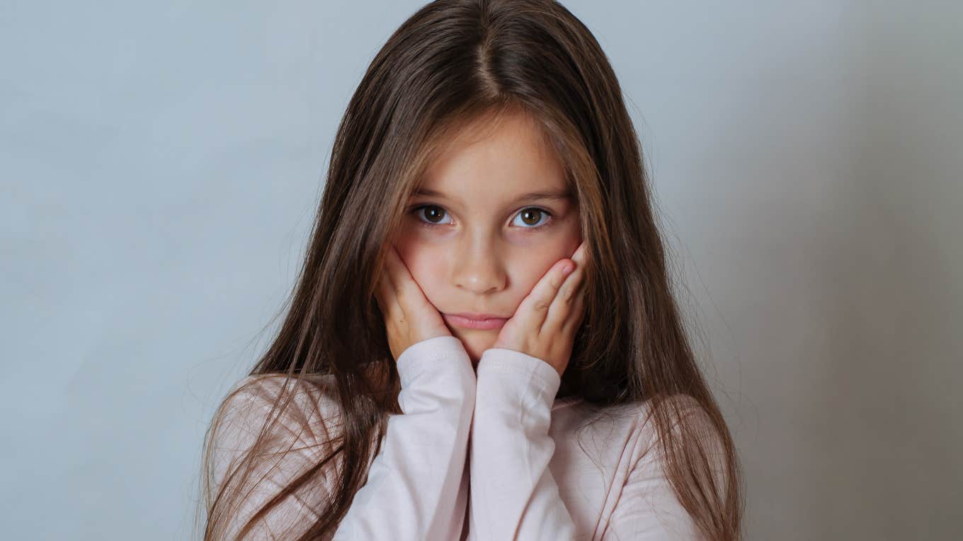 scared, upset little girl with hands over her face