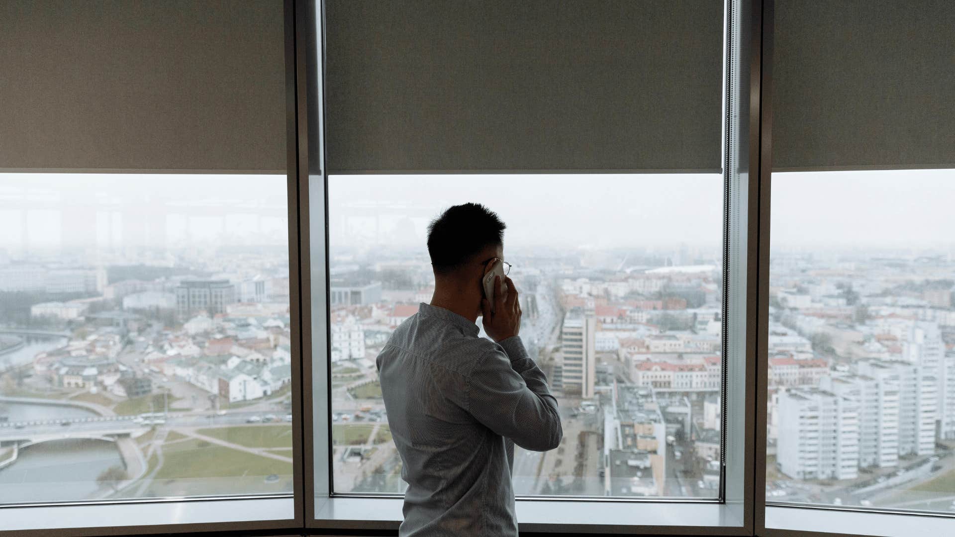 man standing in front of window calling someone