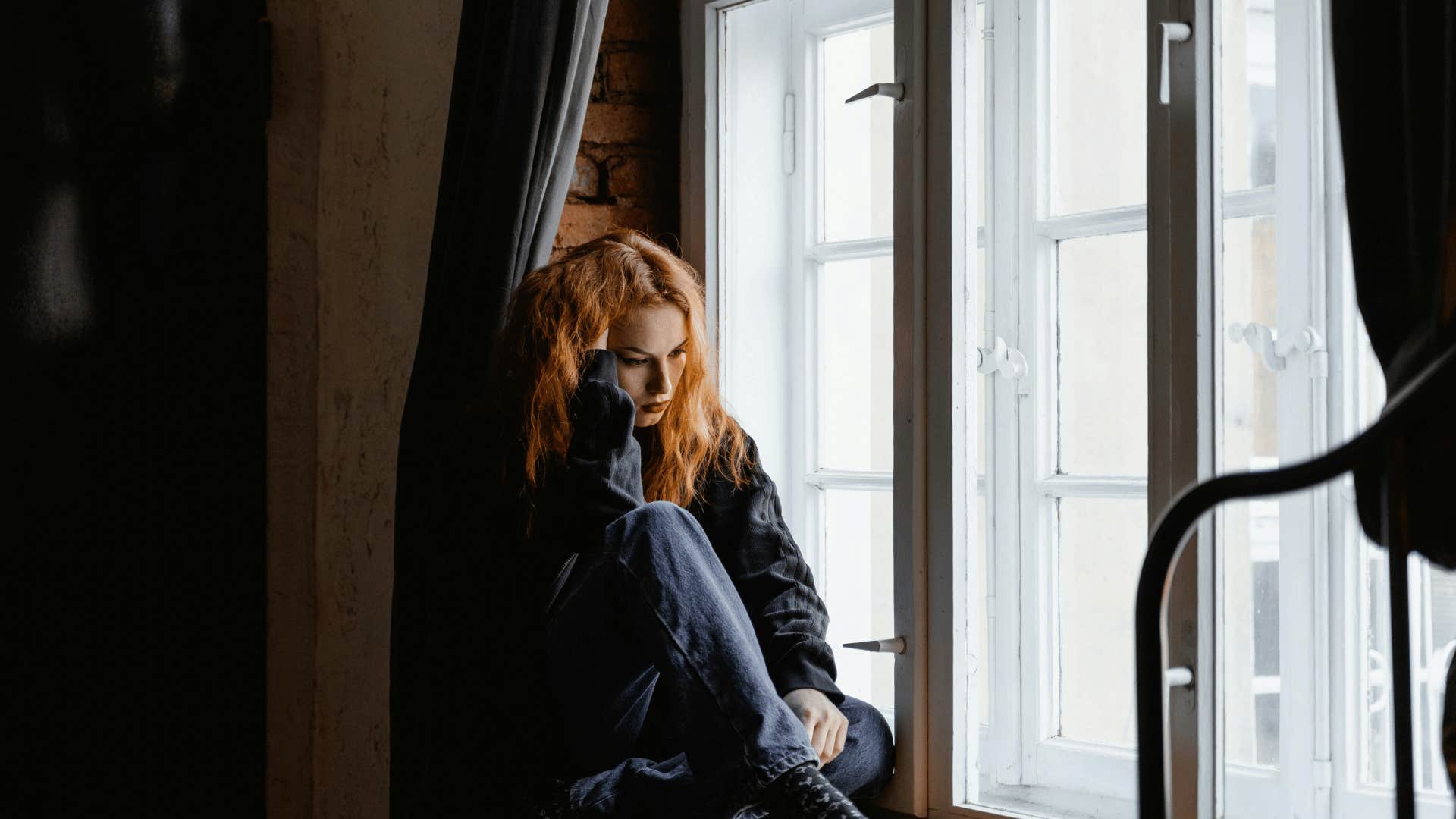 upset woman sitting next to window