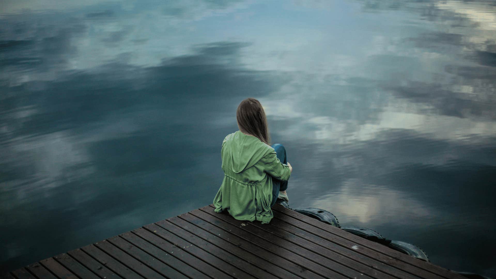 woman sitting alone next to water