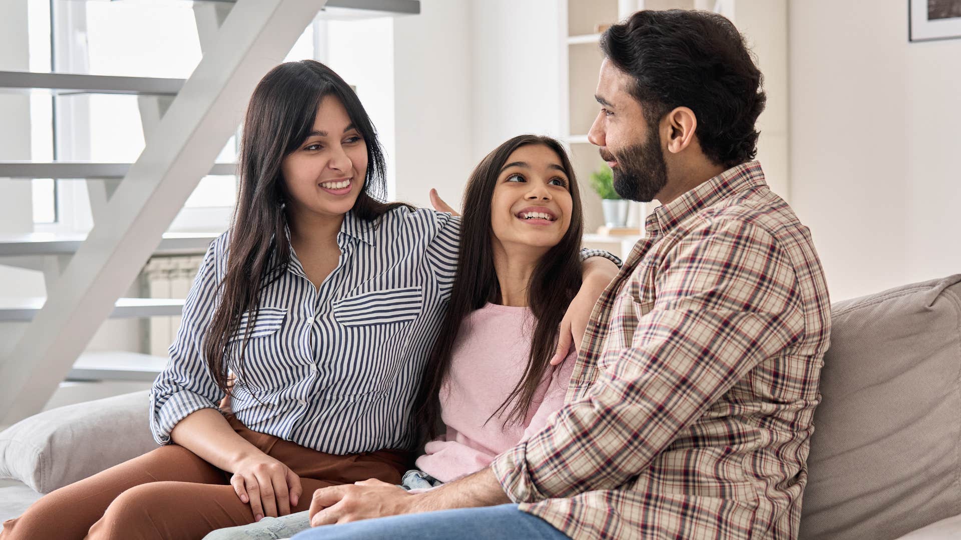 Teenage girl smiling in between her two parents