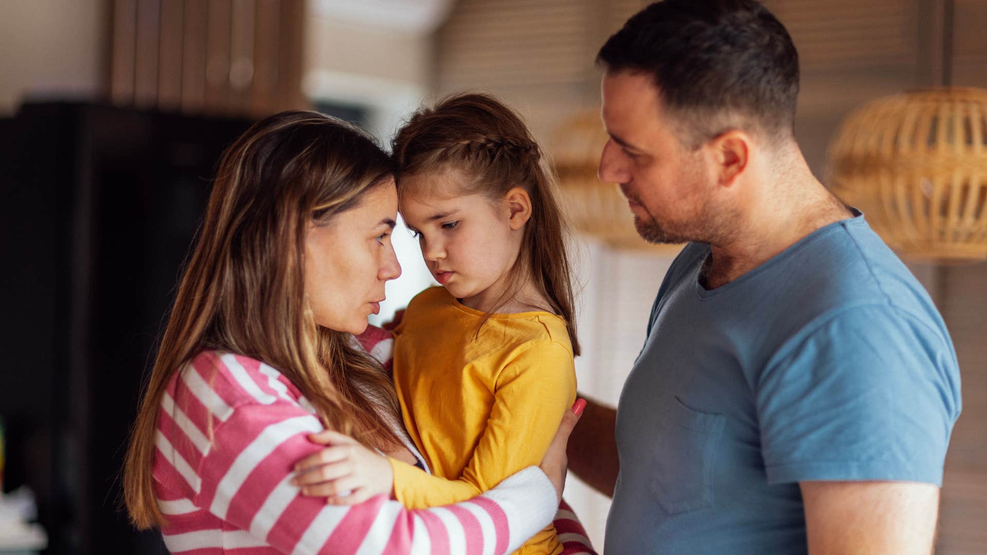 Couple hugging their upset young daughter