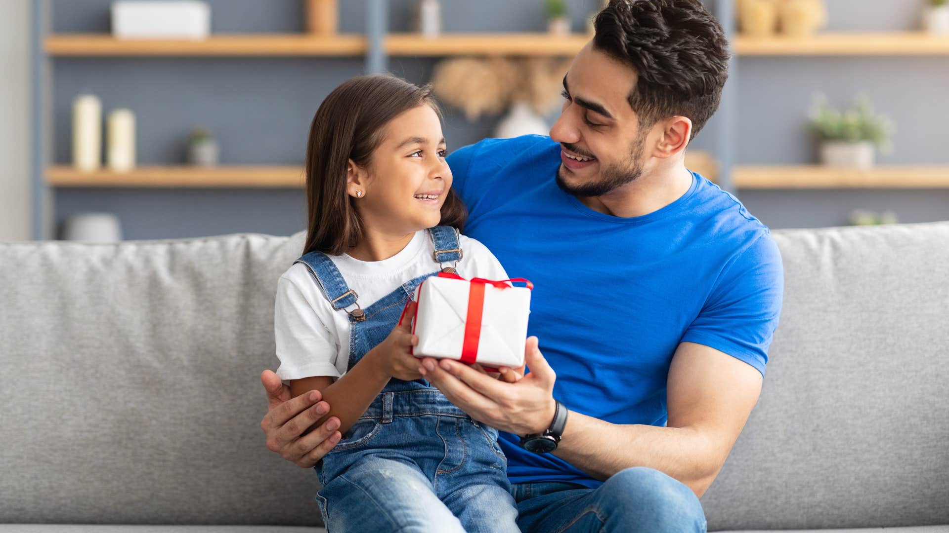 Father smiling and giving a gift to his young daughter