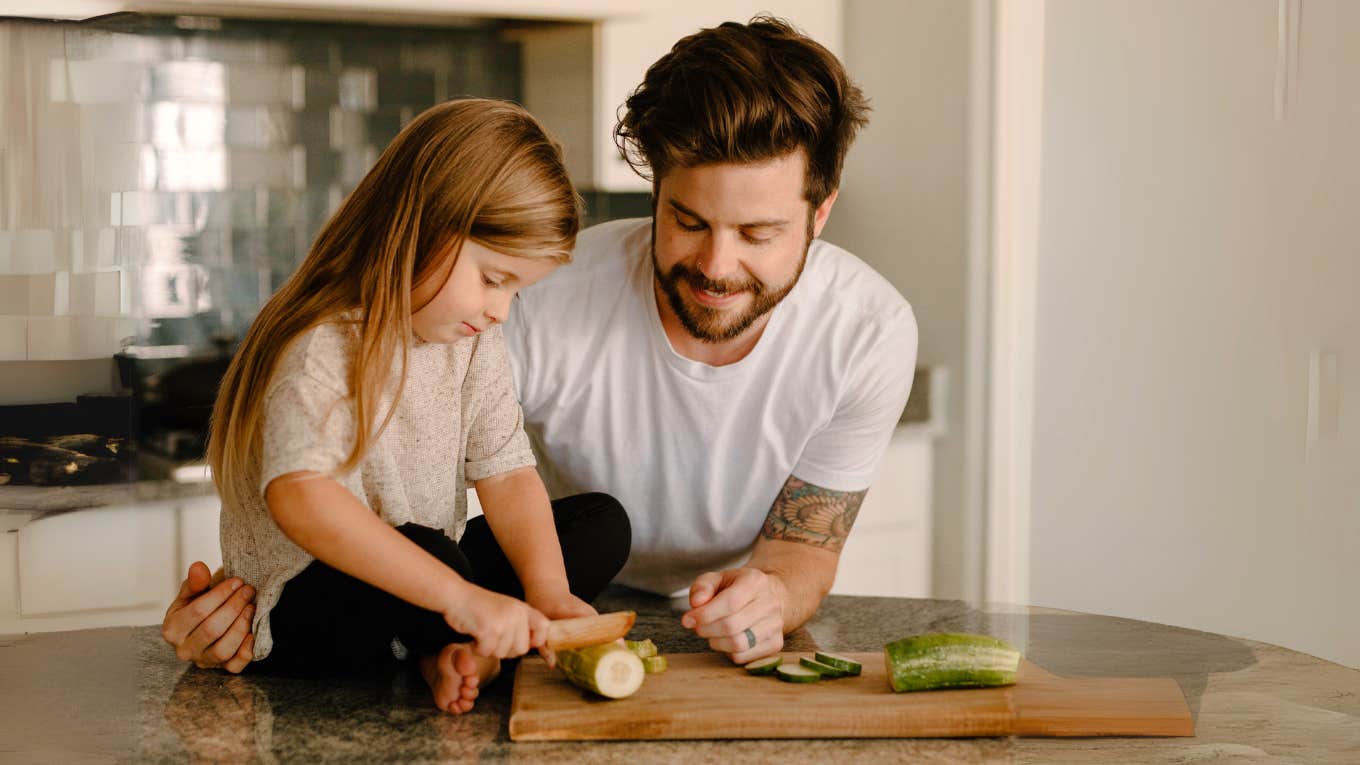 Stay at home millennial father, in the kitchen cooking with daughter while wife is at work.