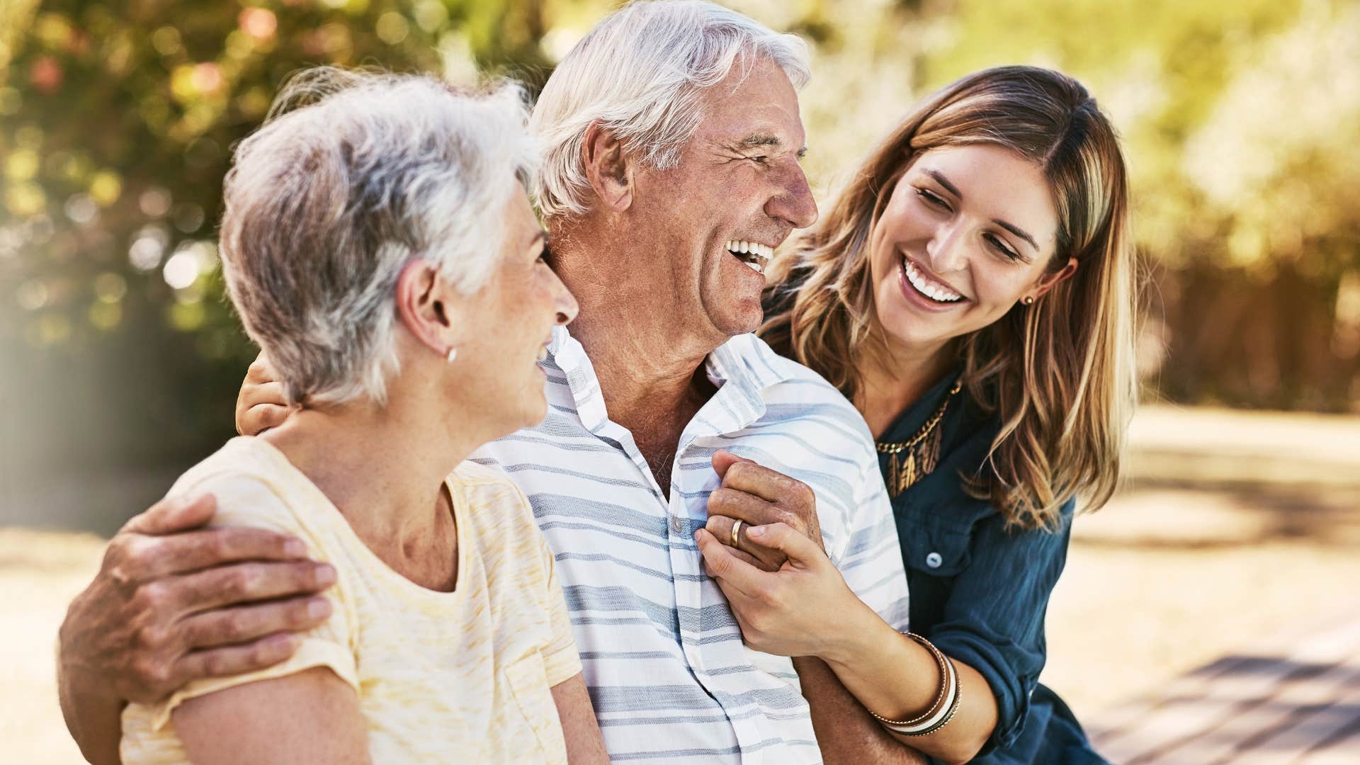 Adult daughter smiling and hugging her parents