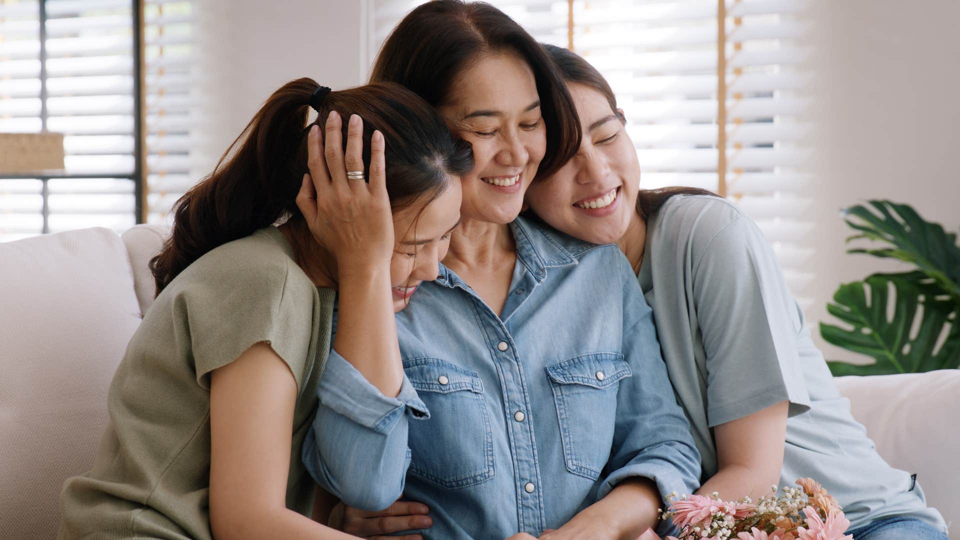 Woman smiling and hugging her two adult daughters