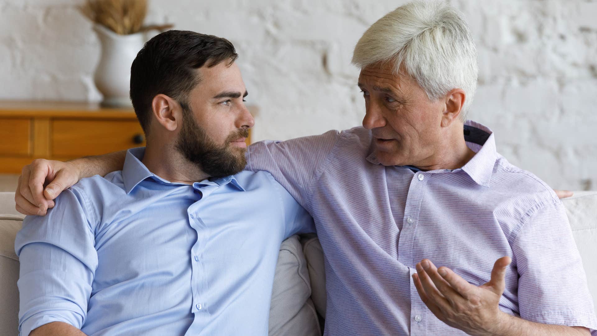 Adult son talking to his dad on the couch