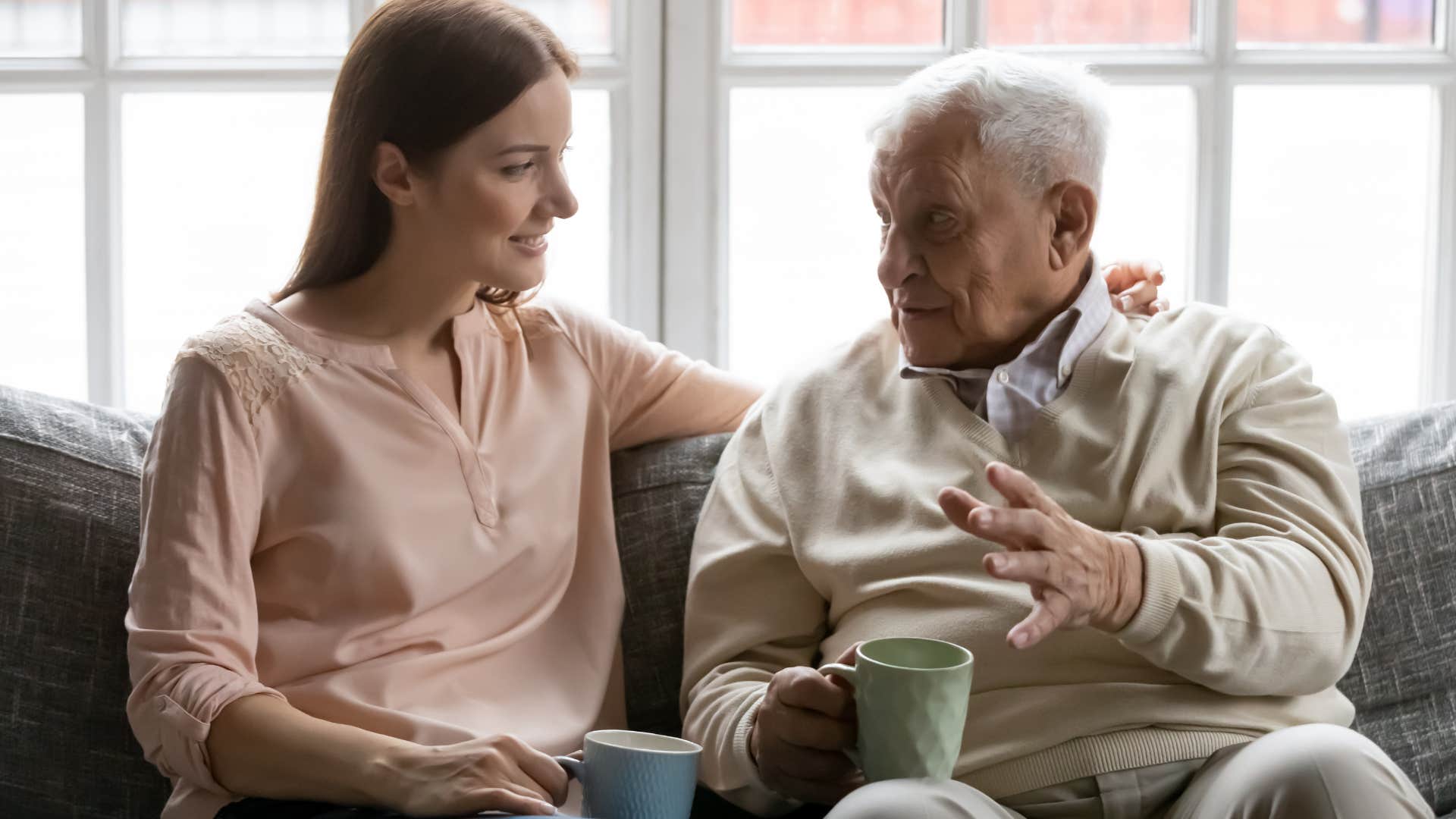 Older man talking to his adult daughter on the couch