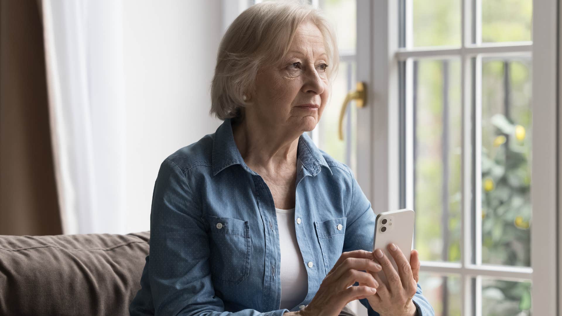 Older woman looking upset holding her cell phone