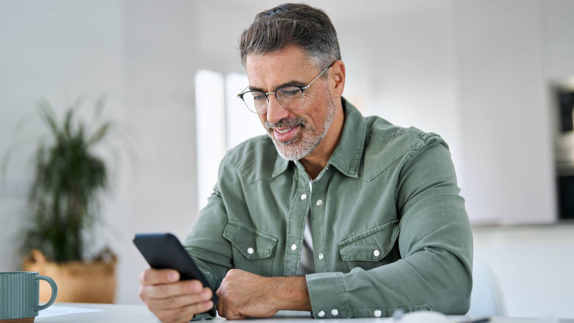 Older man smiling while texting on his phone