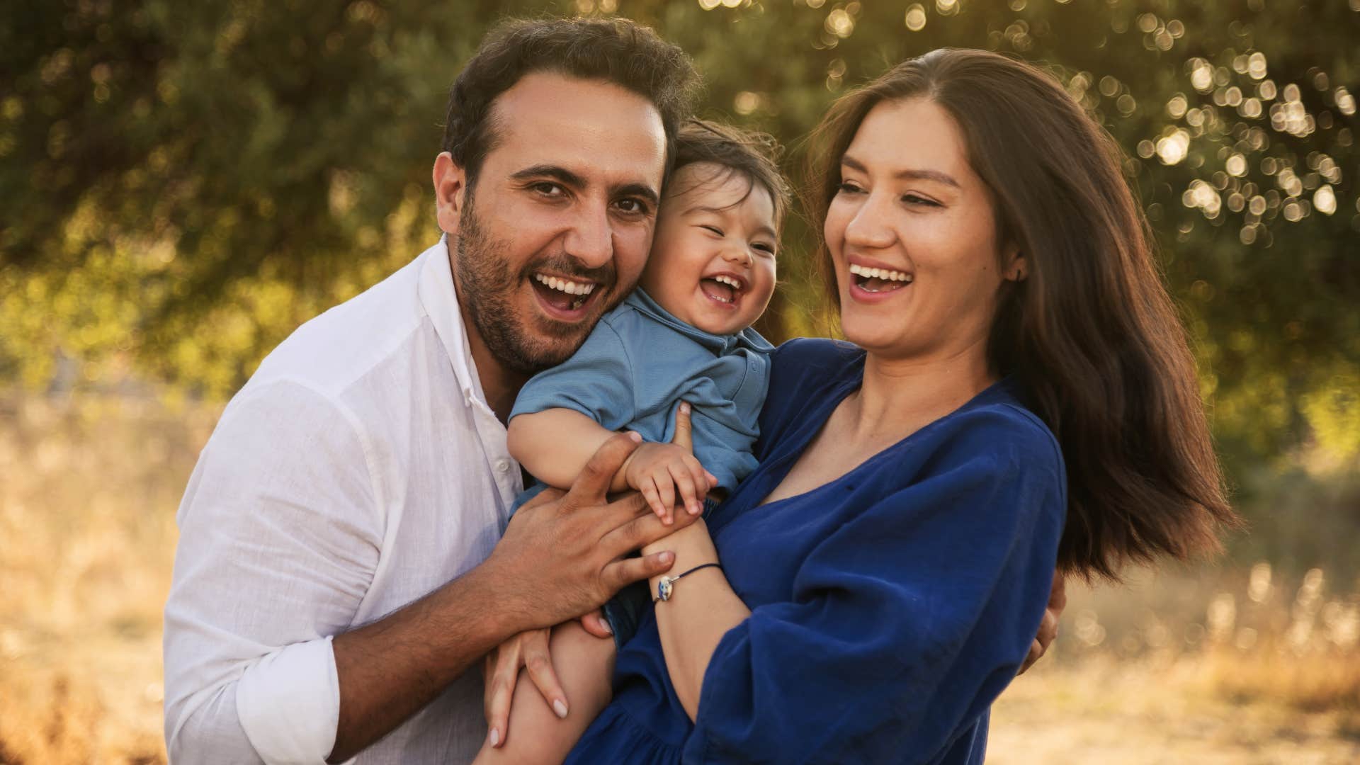 Couple smiling and holding their baby between them