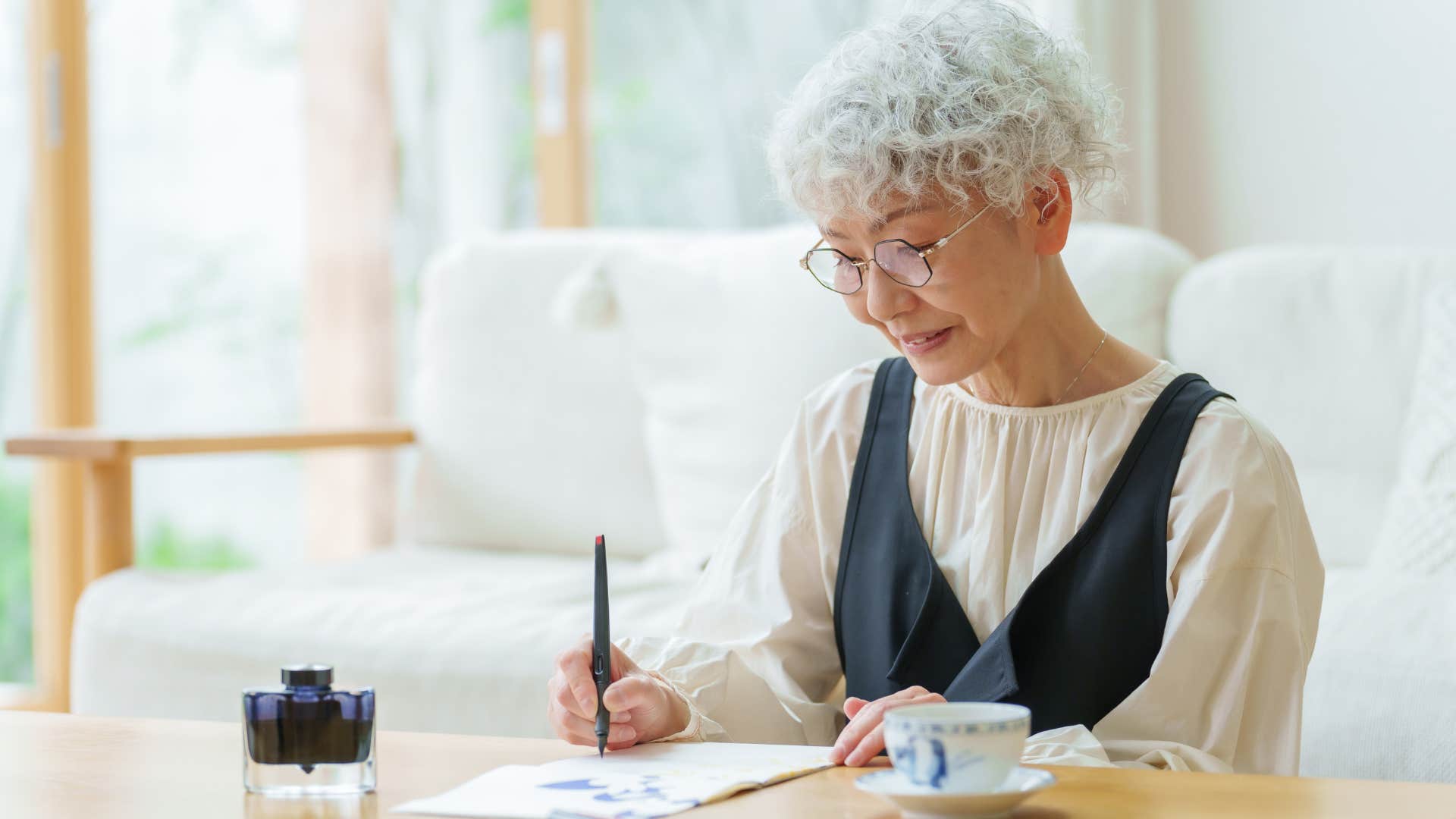 Older woman smiling and writing on a piece of paper