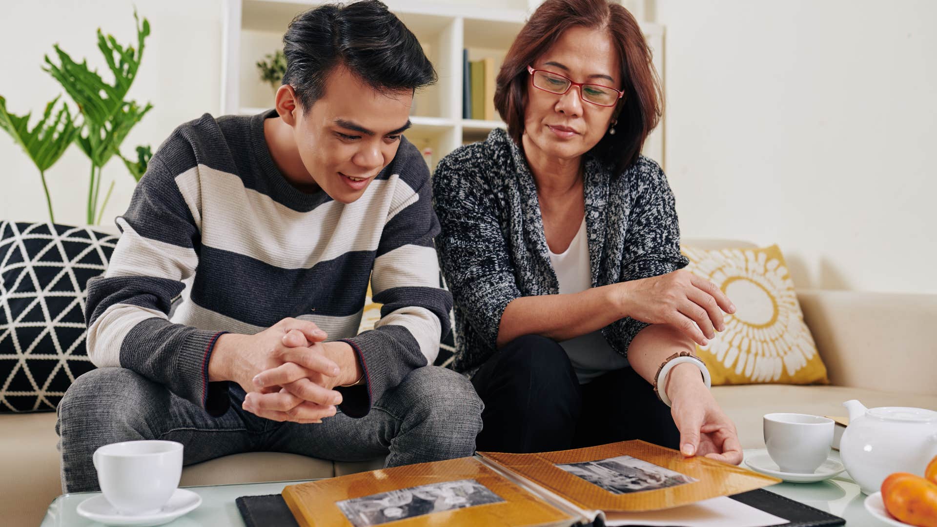 Adult son and mother looking through a photo album together