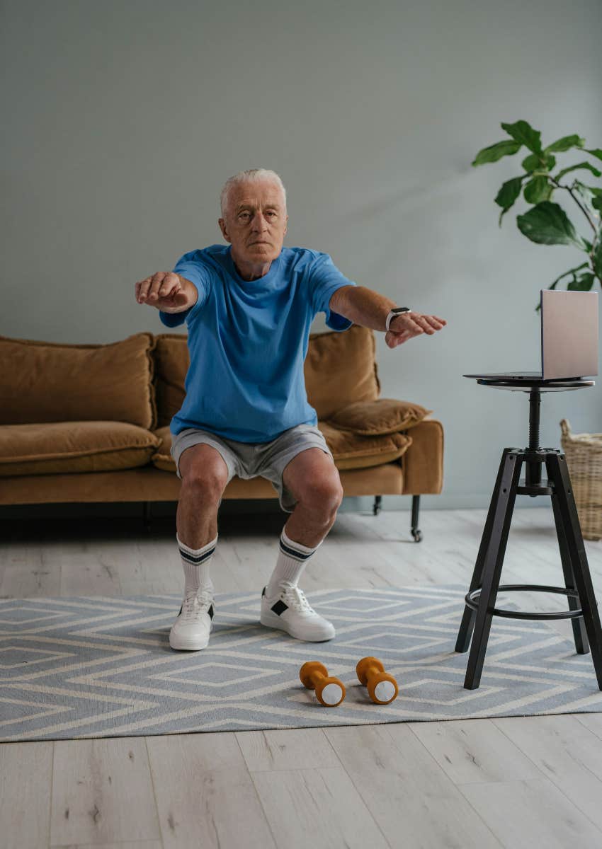 older man doing squats in his living room