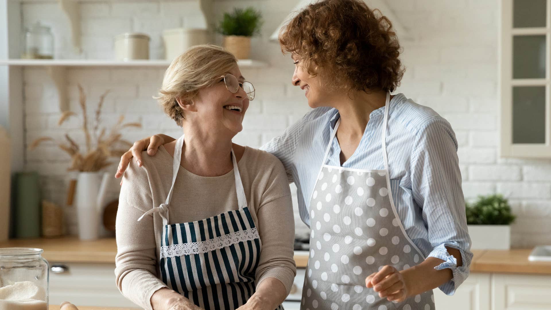 Mother and adult daughter cooking together in the kitchen.