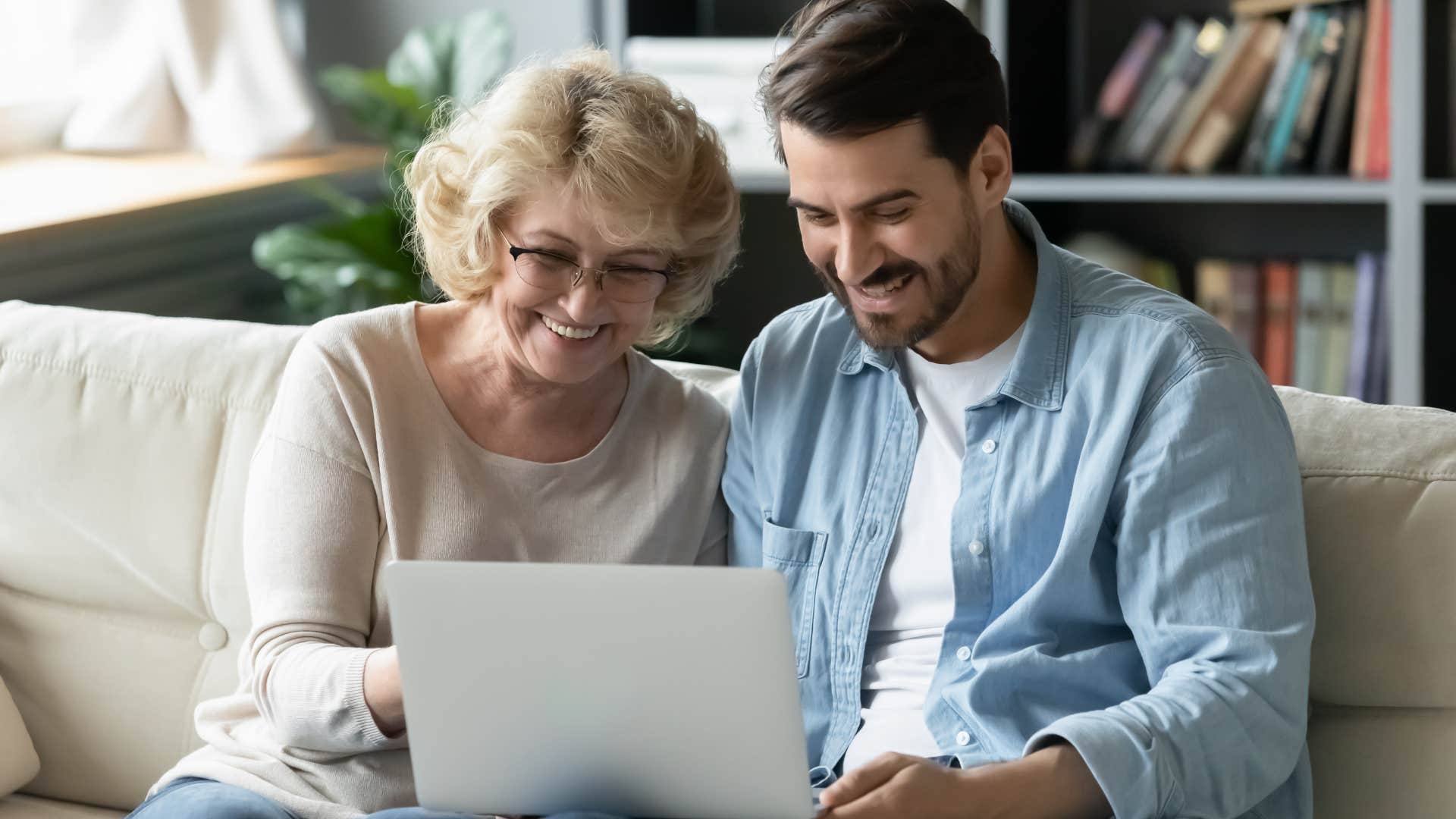 Woman smiling looking at her adult son's laptop.